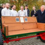 JCB apprentices mark anniversary with unique ‘listening bench’ creation Lord Bamford and JCB apprentices at Listening Bench