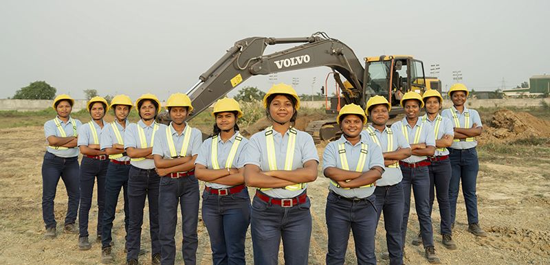 Female plant operators standing in front of Volvo excavator