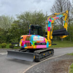 Distinctive digger set to raise vital funds for children’s charity Rainbow-coloured excavator on site