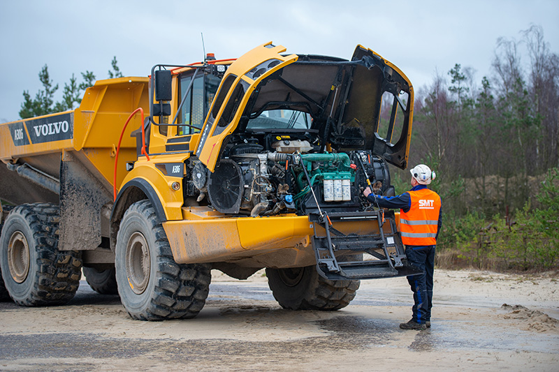 Worker inspecting engine of Volvo dump truck